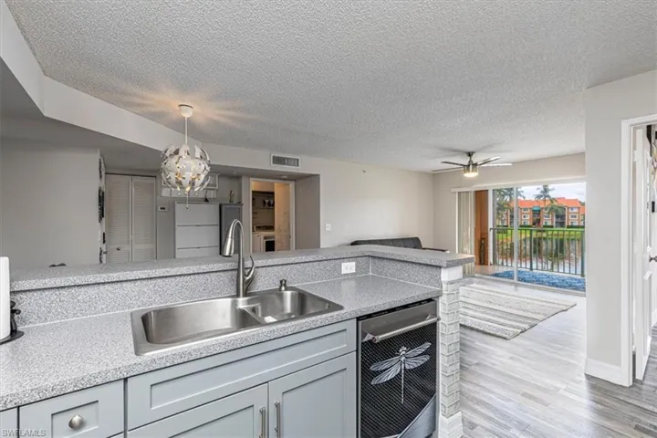 Kitchen featuring light wood finished floors, open floor plan, a textured ceiling, hanging light fixtures, and a ceiling fan
