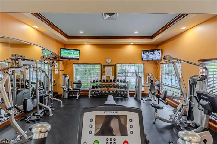 Exercise room with recessed lighting, crown molding, and a raised ceiling