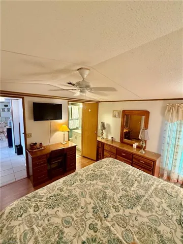 Bedroom with light wood vinyl floors, a textured ceiling, a ceiling fan, and ornamental molding