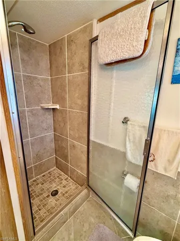 Full bath featuring a stall shower, a textured ceiling, and tile patterned floors