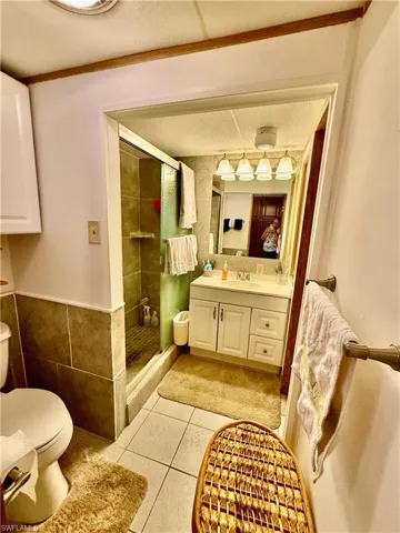 Main bathroom featuring a tub with shower, vanity, light tile patterned flooring, a textured ceiling, and crown molding