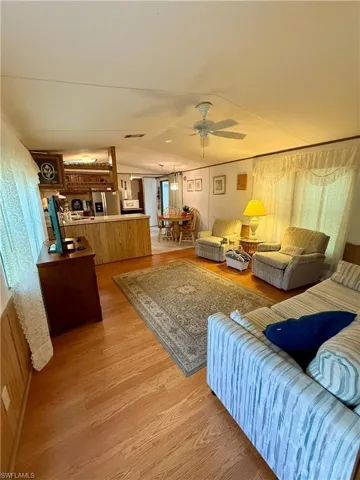 Living area featuring light wood vinyl floors, lofted ceiling, and ceiling fan