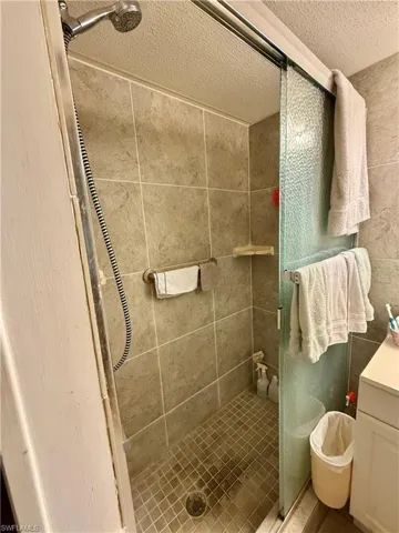 Main full bath featuring a shower stall, vanity, and a textured ceiling