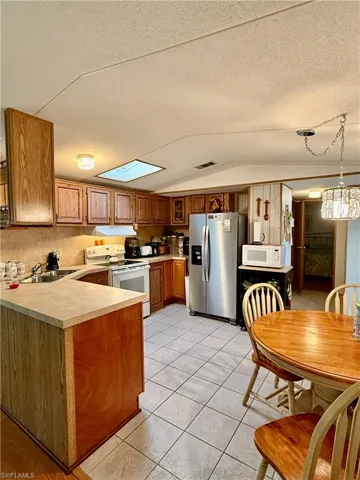 Kitchen featuring white appliances, including dishwasher and disposal,  and vaulted ceiling.