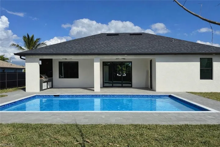 Back of house with a patio area, exterior kitchen, roof with shingles, and stucco siding