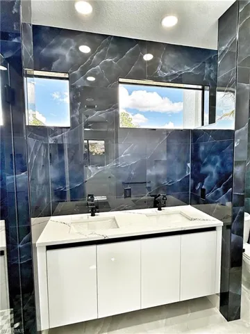 Bathroom with double vanity, tile walls, and recessed lighting