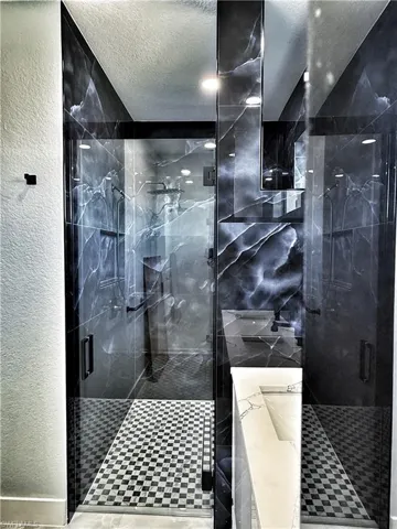 Bathroom with a textured wall, a marble finish shower, and a textured ceiling