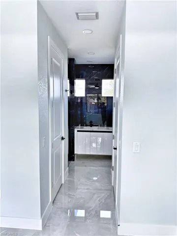 Corridor featuring a textured wall and light marble finish floors