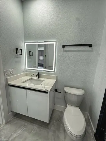 Half bathroom featuring a textured wall and vanity