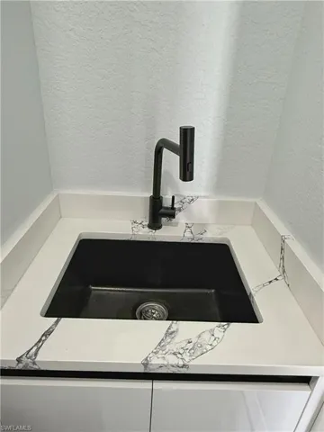 Kitchen view of a textured wall, white cabinets, and light countertops