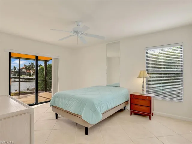 Bedroom featuring access to exterior, a water view, ceiling fan, and light tile patterned flooring