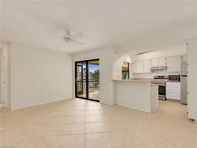 Kitchen featuring kitchen peninsula, appliances with stainless steel finishes, ceiling fan, light tile patterned floors, and white cabinetry