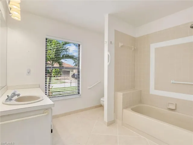 Full bathroom featuring tile patterned floors, vanity, tiled shower / bath combo, and toilet