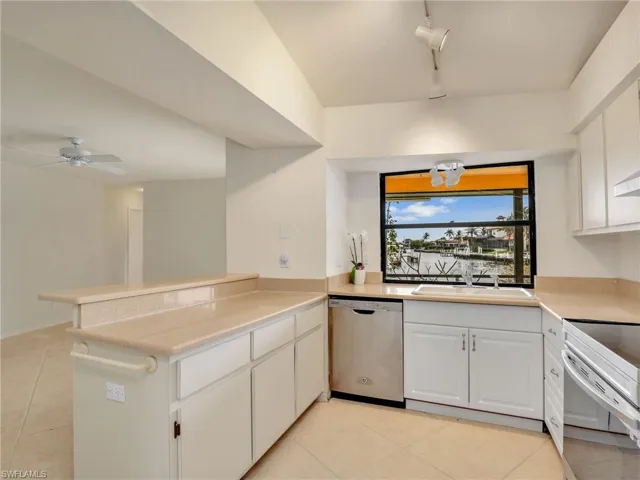 Kitchen featuring kitchen peninsula, rail lighting, white cabinets, ceiling fan, and dishwasher