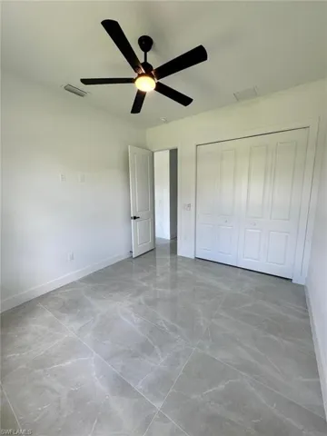 Unfurnished bedroom with ceiling fan, a closet, and light marble finish flooring
