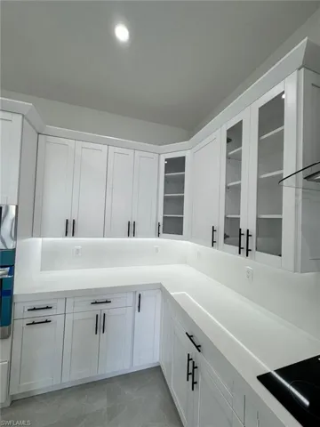 Kitchen with white cabinets, appliances with stainless steel finishes, recessed lighting, and glass insert cabinets