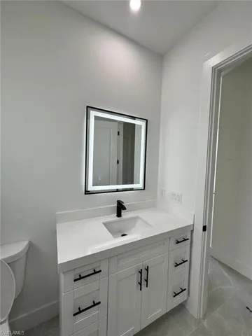 Half bath with vanity, light marble finish floors, and recessed lighting