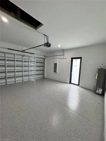 Garage featuring water heater, a garage door opener, and electric panel