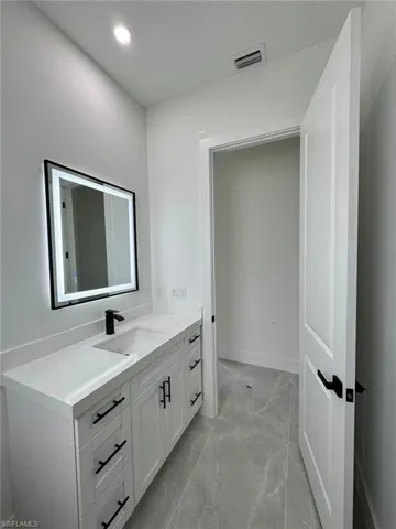 Bathroom with vanity, light marble finish flooring, and recessed lighting