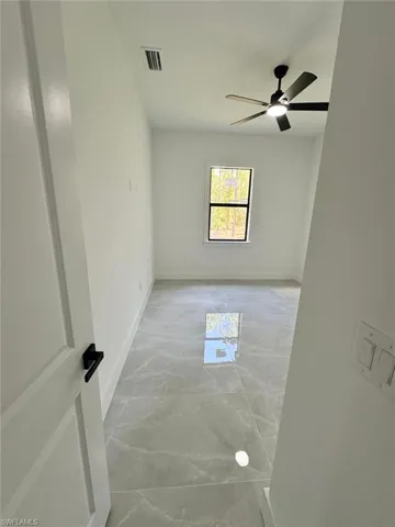 Empty room with light marble finish flooring and a ceiling fan