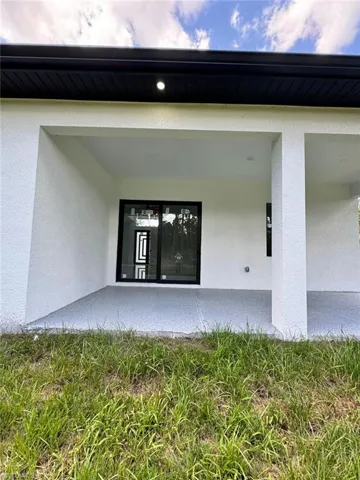 View of exterior entry with stucco siding and a patio
