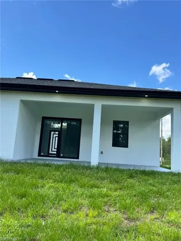 Back of property with stucco siding and a yard
