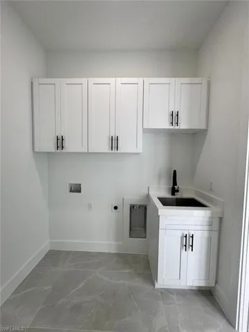 Laundry room with cabinet space, electric dryer hookup, washer hookup, and light marble finish flooring