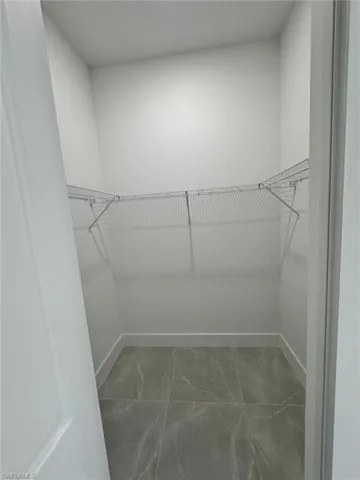 Spacious closet featuring light marble finish floors