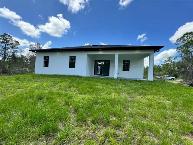 Rear view of property with stucco siding, a patio, and a yard