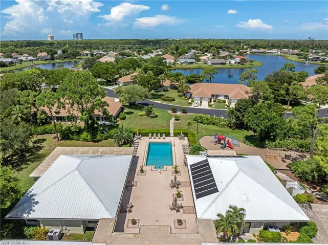 Aerial view of residential area featuring a pool and a nearby body of water