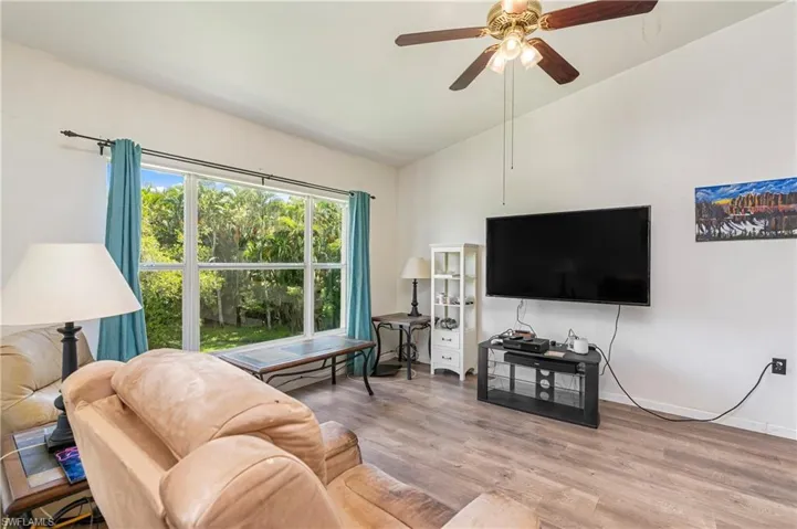 Living area featuring wood finished floors, a ceiling fan, and vaulted ceiling
