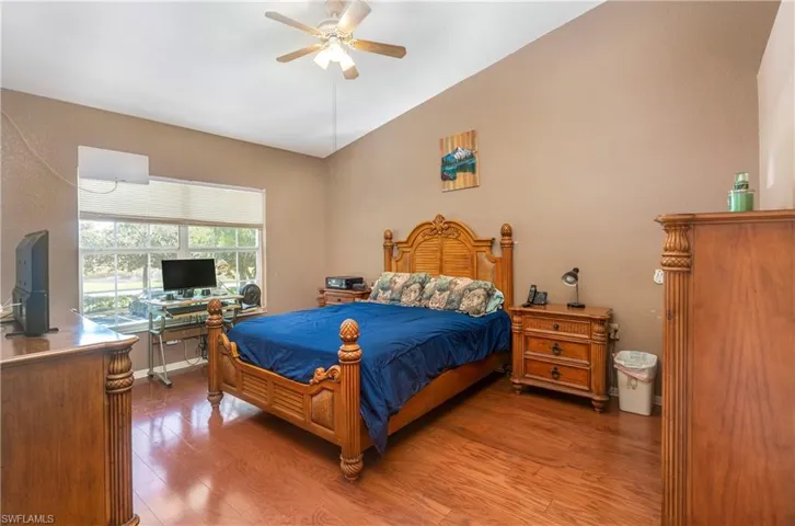 Bedroom featuring an office area, wood finished floors, ceiling fan, and vaulted ceiling