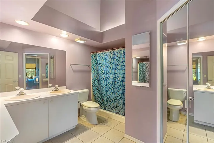 Full bathroom featuring light tile patterned floors, double vanity, recessed lighting, and a shower with curtain