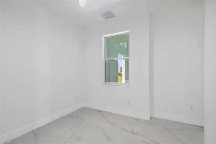 Spare room featuring marble finish floor, baseboards, and visible vents