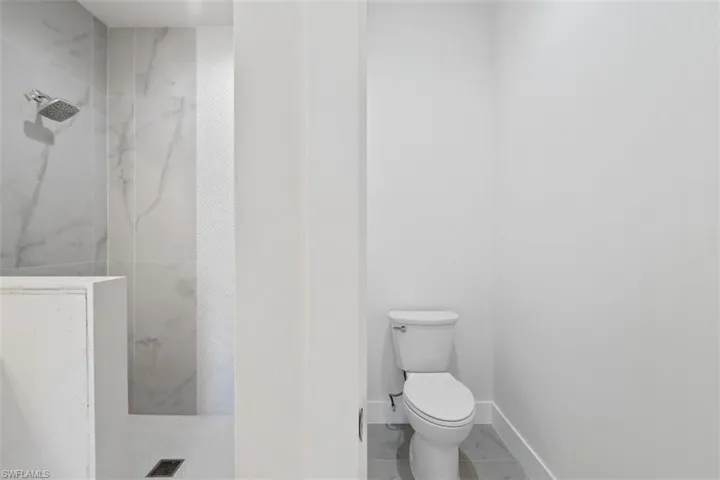 Full bath featuring a marble finish shower, toilet, baseboards, marble finish floor, and visible vents