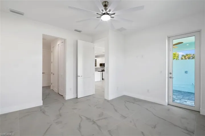 Empty room with marble finish floor, baseboards, visible vents, and a ceiling fan