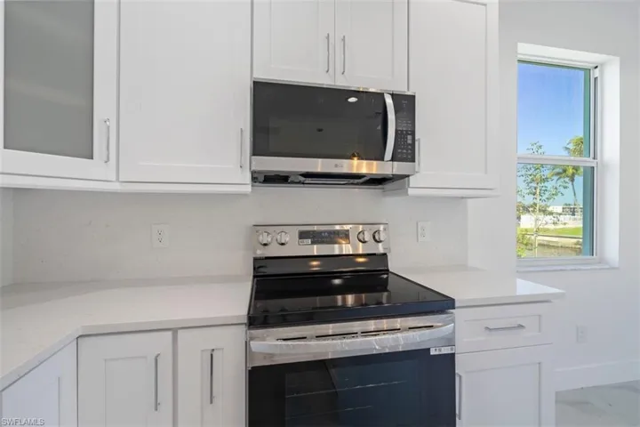 Kitchen with glass insert cabinets, white cabinetry, and stainless steel appliances