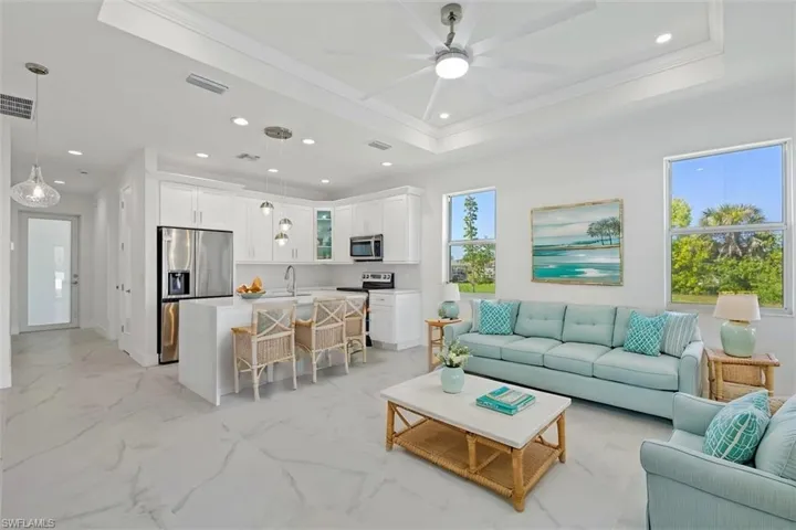Living area with a ceiling fan, recessed lighting, a tray ceiling, and crown molding