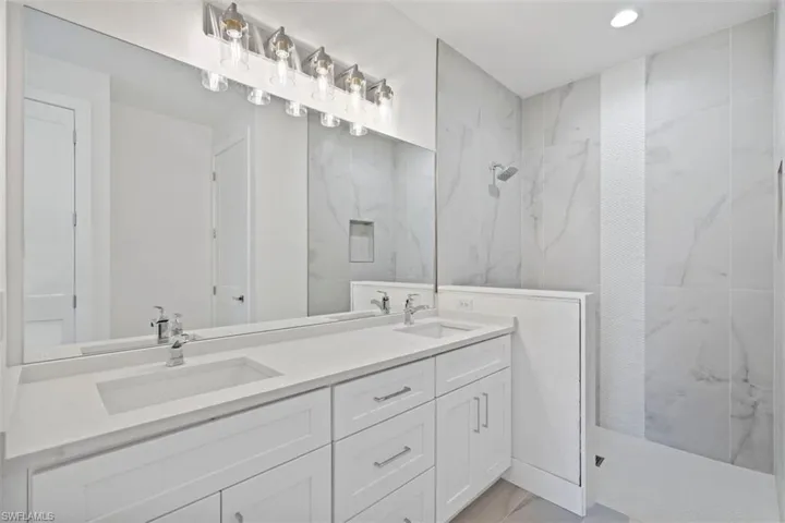 Full bathroom with a marble finish shower, marble finish floor, a sink, and double vanity