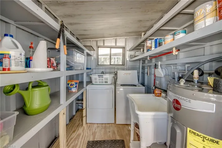 Laundry room with water heater, light wood-style floors, and washer and clothes dryer