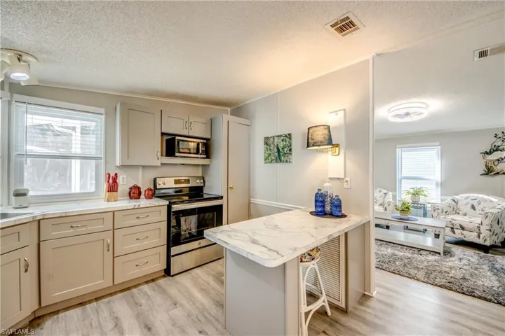 Kitchen with plenty of natural light, crown molding, stainless steel appliances, a textured ceiling, and light countertops