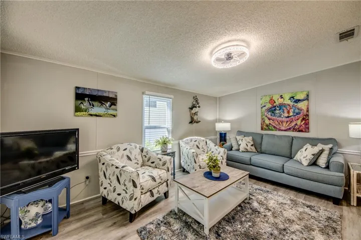 Living room featuring a textured ceiling, wood finished floors, and a decorative wall