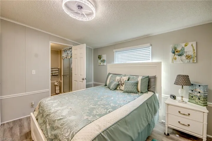 Bedroom featuring light wood-style flooring, a textured ceiling, and ornamental molding