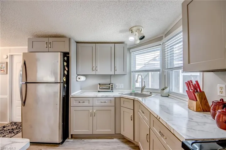 Kitchen with freestanding refrigerator, light countertops, a textured ceiling, light wood-style flooring, and gray cabinetry