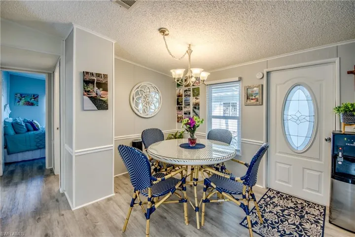 Dining area featuring wood finished floors, a textured ceiling, ornamental molding, and a chandelier
