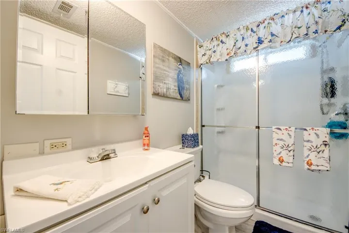 Bathroom with a textured ceiling, a stall shower, vanity, and crown molding