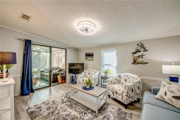 Living area featuring a textured ceiling, crown molding, and light wood-style flooring