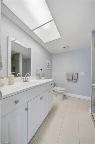 Bathroom featuring a white vanity with silver-toned hardware, a rectangular sink, and a mirrored wall cabinet