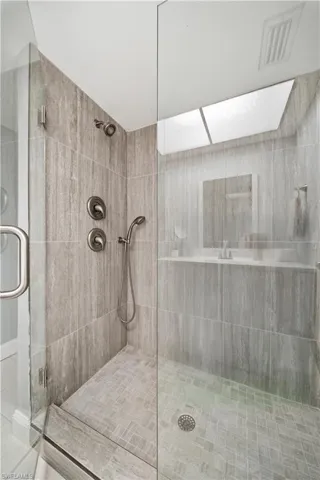 Glass-enclosed shower featuring large format tile walls and a mosaic tile floor