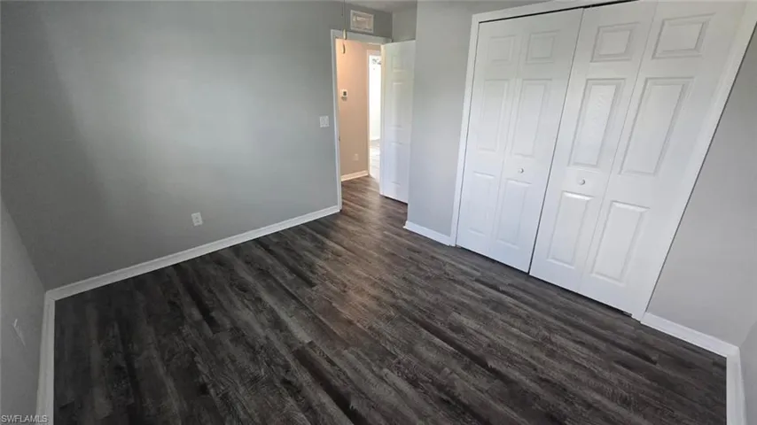 Unfurnished bedroom featuring dark wood-style flooring and a closet